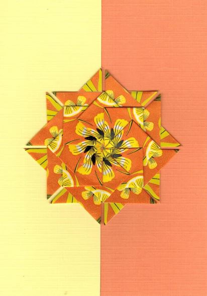Een geel oranje rozet op een kaart met bladwijzer motief. <br>Deze rozet is gemaakt uit een deel van oranje Clipper theezakjes.