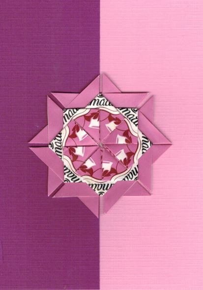 Een wit roze rozet op een kaart met donkerpaars bladwijzer motief. <br>Deze rozet is gemaakt uit Amarti harmony  theezakjes.